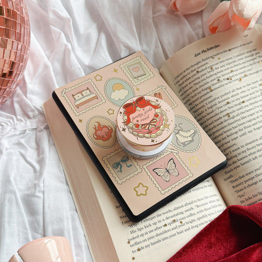 Small round container with a lid featuring a design of a strawberry on top of an open book.