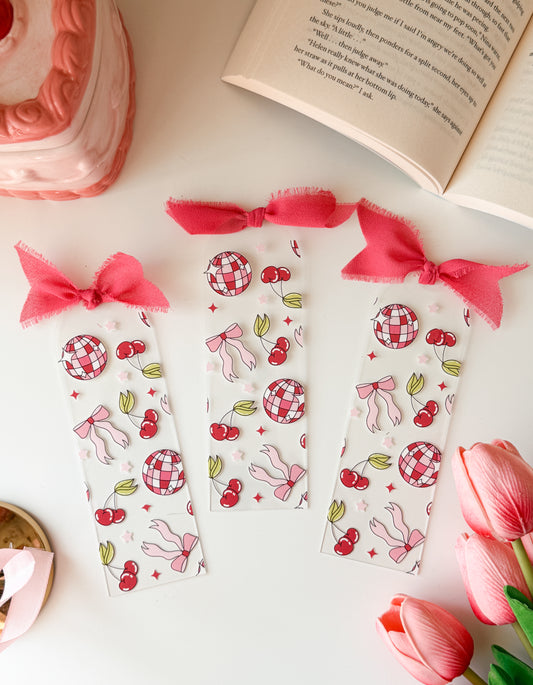 Set of decorative bookmarks with pink ribbons on a white surface with a book and tulips.