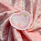 A scalloped die-cut sticker with the text 'Doing My Best' in pink lettering, surrounded by cute illustrations and small holographic star accents, placed on a draped pink glittery fabric background.